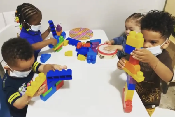 Four children playing with legos on a table.